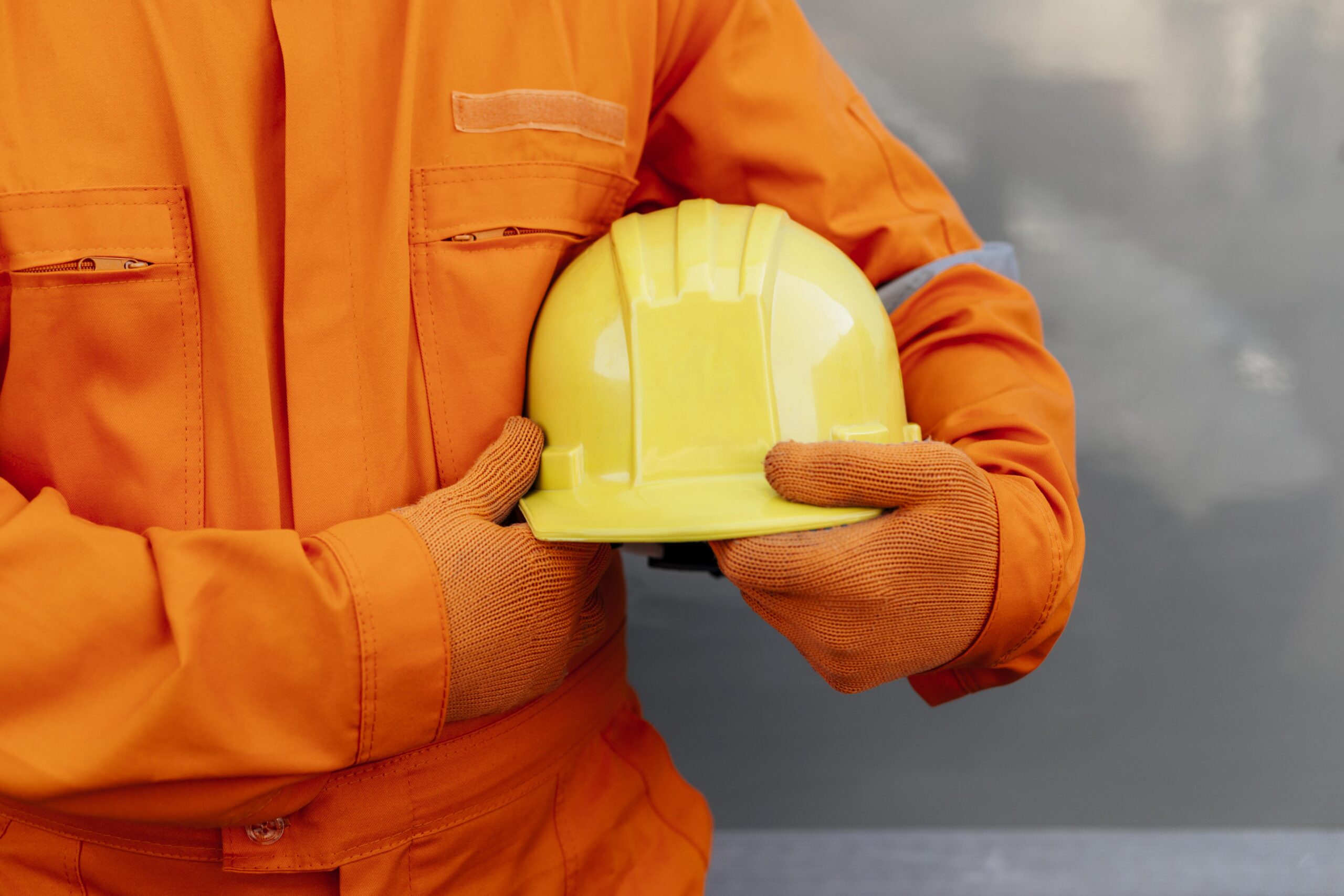 front view worker uniform holding hard hat
